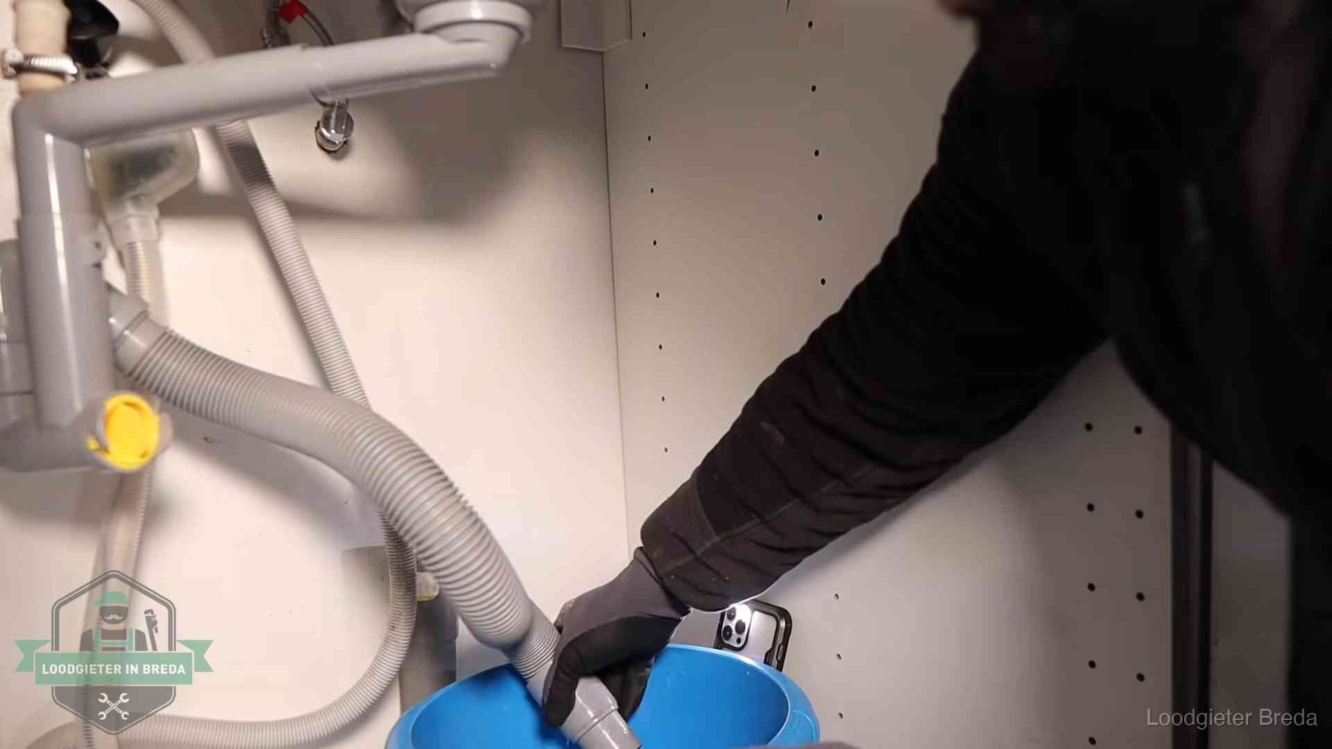 Afvoerslang loopt leeg in een emmer onder de gootsteen in Breda, een klus die je zelf kunt doen