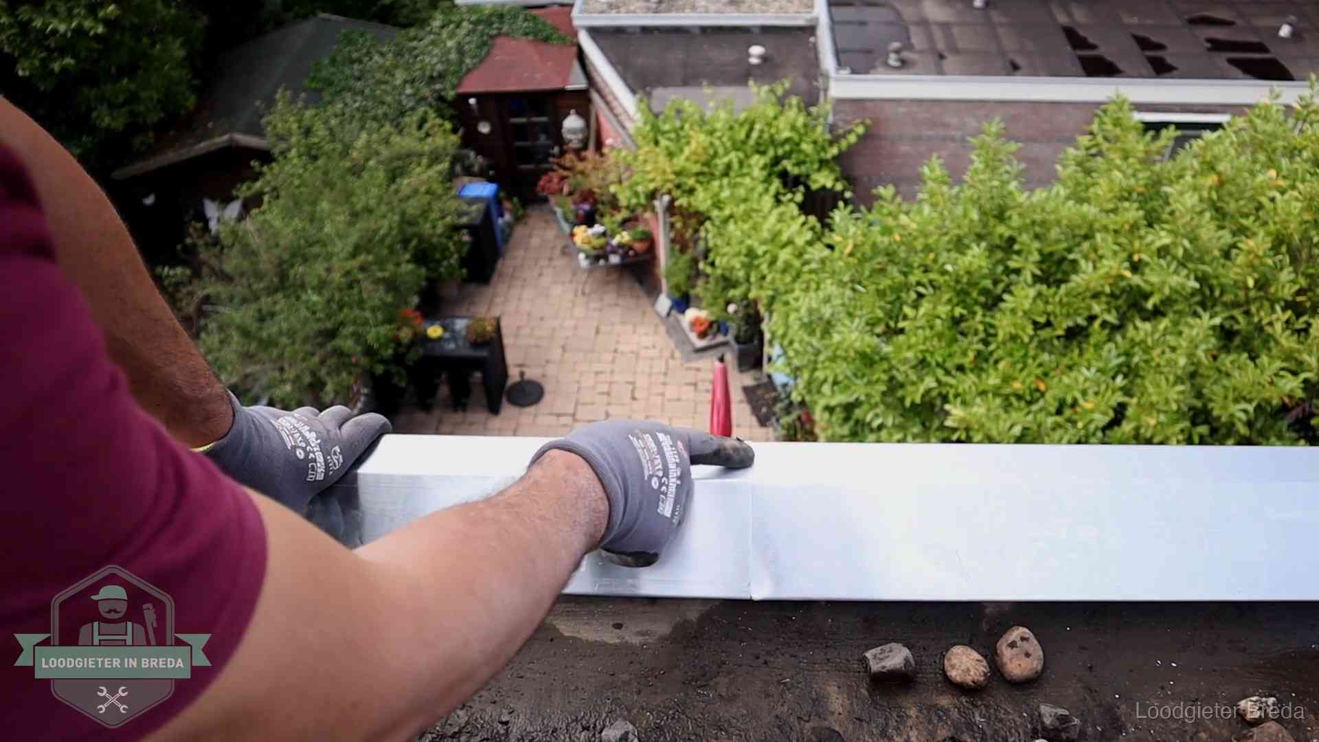 Daklekkage geregeld in Breda Vakman plaatst een daktrim op de dakrand van een woning in Breda