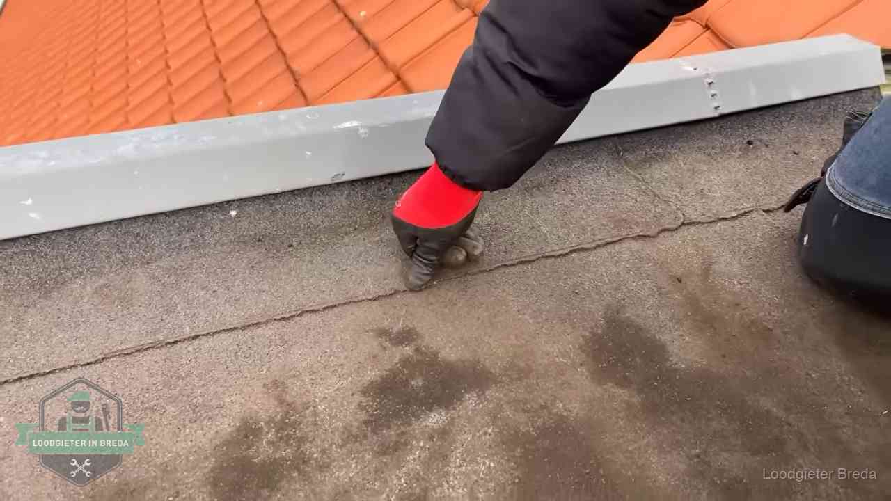 Lekkage bij de naad van een plat dak in Breda Vakman wijst een naad met vochtplekken aan op een bitumen plat dak in Breda