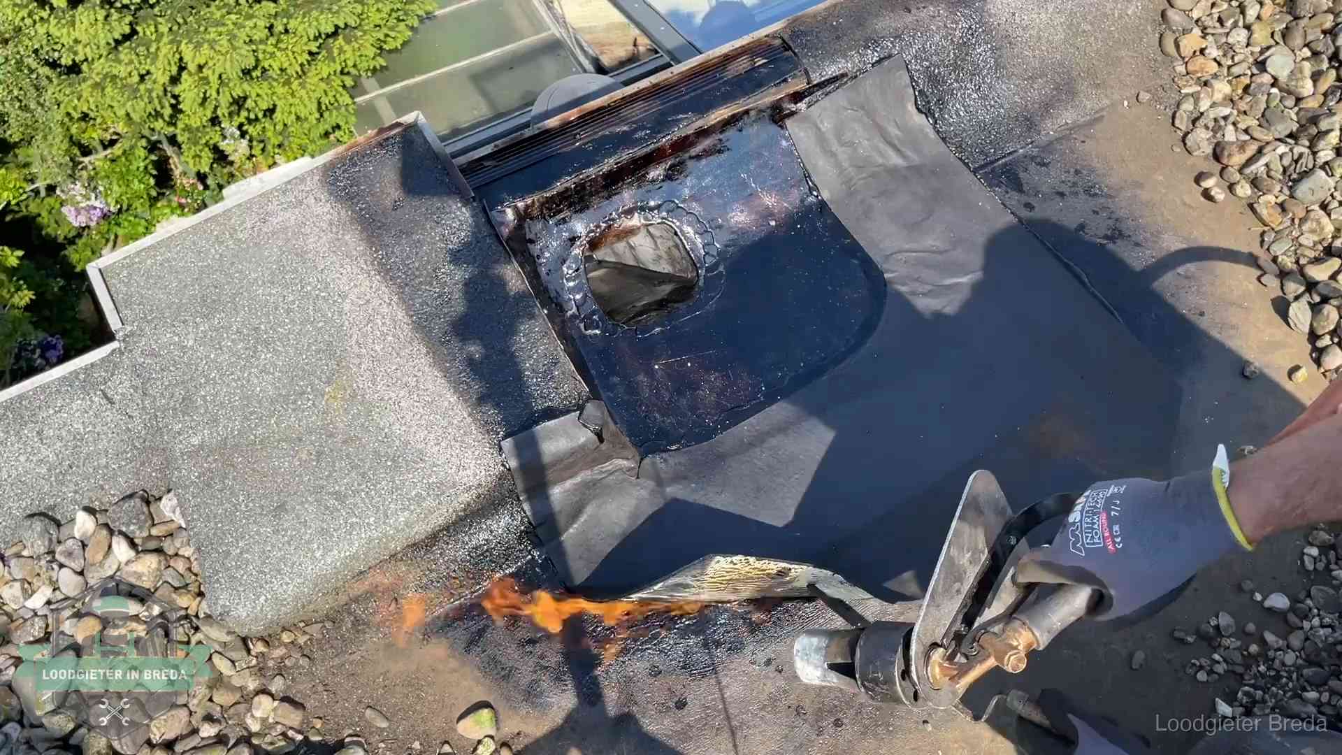 Daklekkage repareren in Breda Dakdekker brandt bitumen rond een doorvoer tijdens een daklekkage-reparatie in Breda