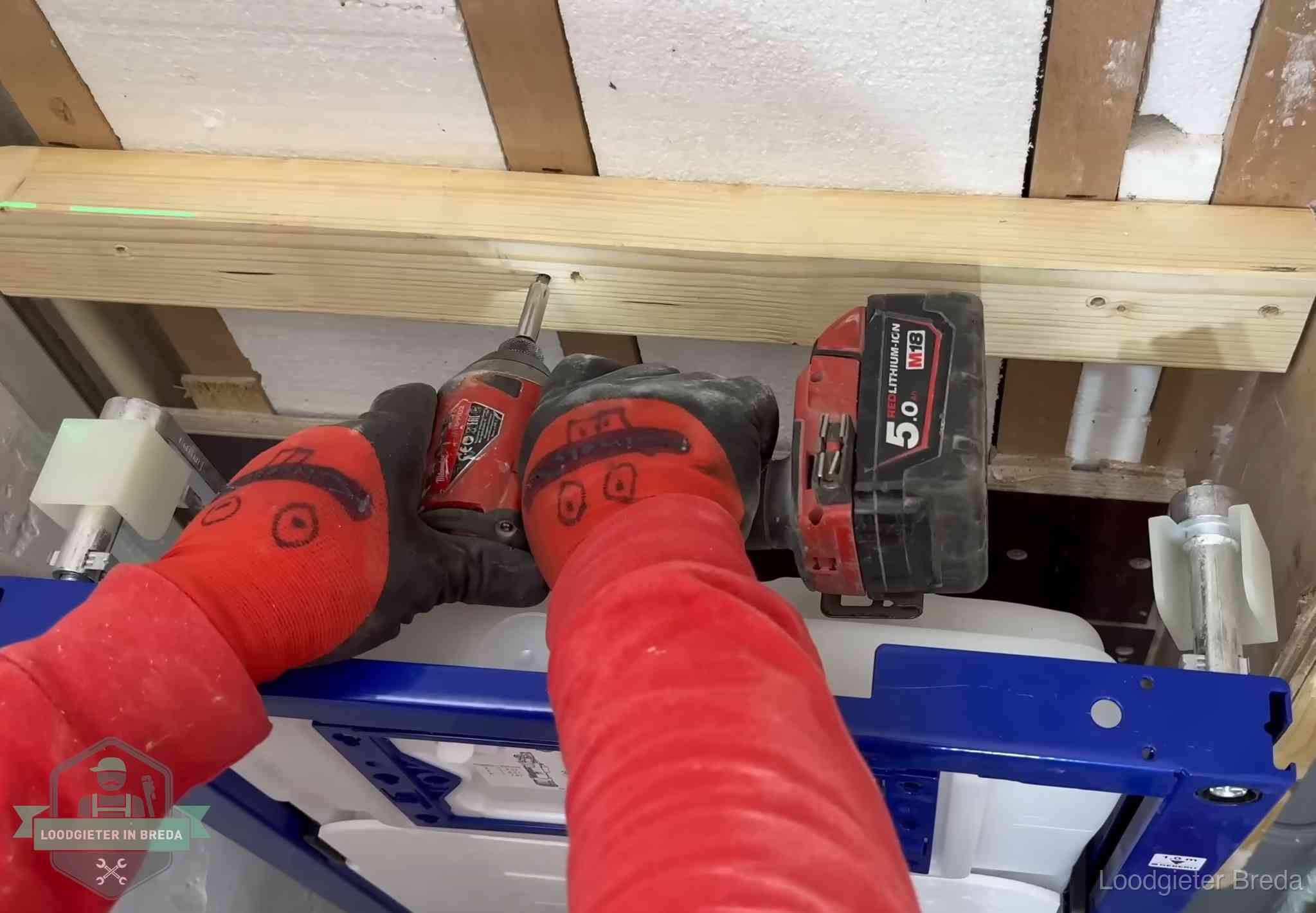 Monteur bevestigt een inbouwreservoir voor een hangend toilet in Breda