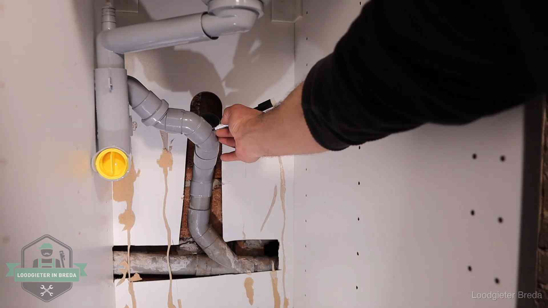 Loodgieter voor verhuurders en bedrijven in Breda Loodgieter markeert een pvc-afvoerbuis onder een gootsteen in Breda