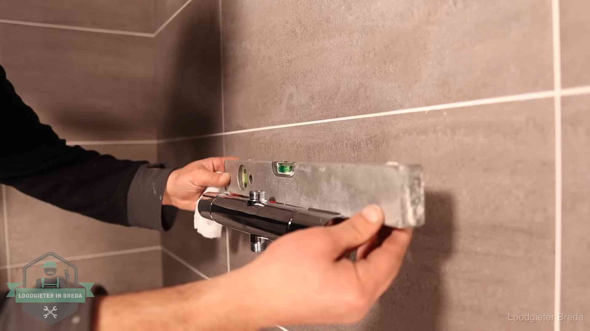 Loodgietersbedrijf voor sanitair in Breda Loodgieter lijnt een douchekraan uit met een waterpas in een woning in Breda