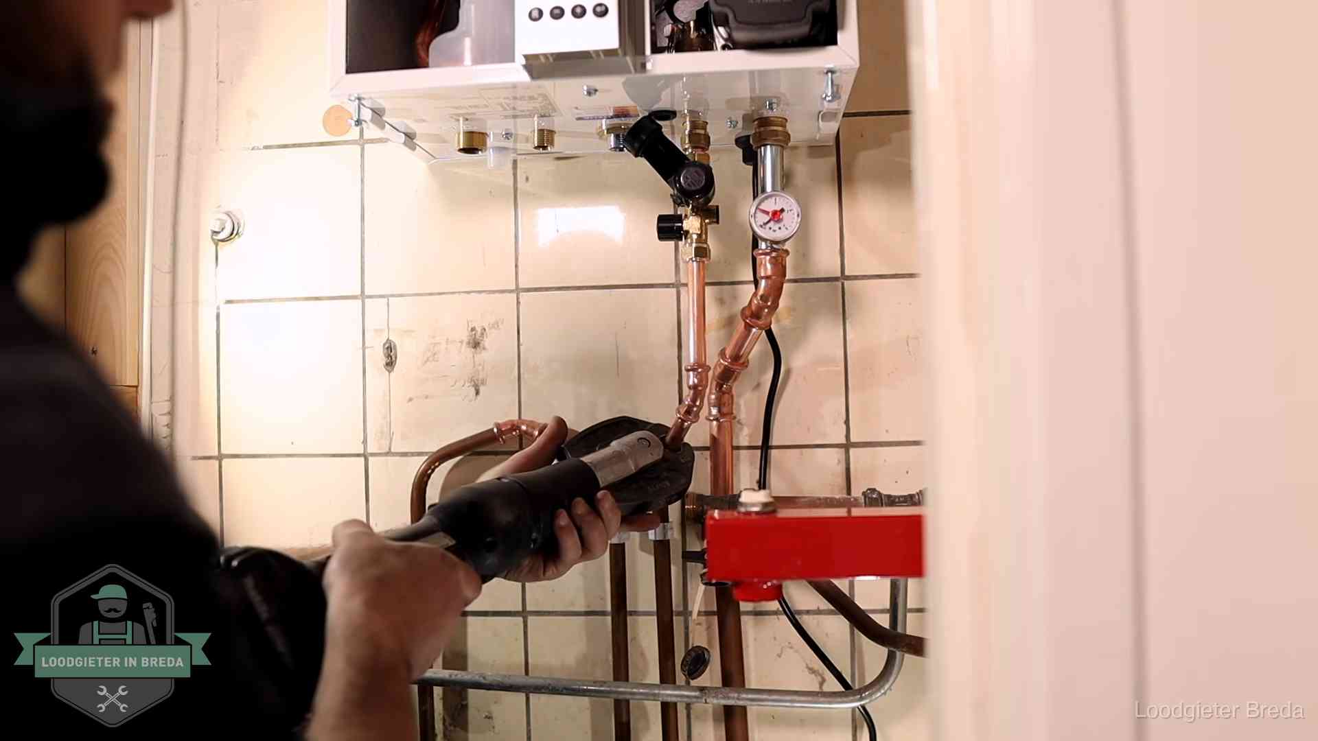 Monteur werkt aan de leidingen onder een cv-ketel in Breda