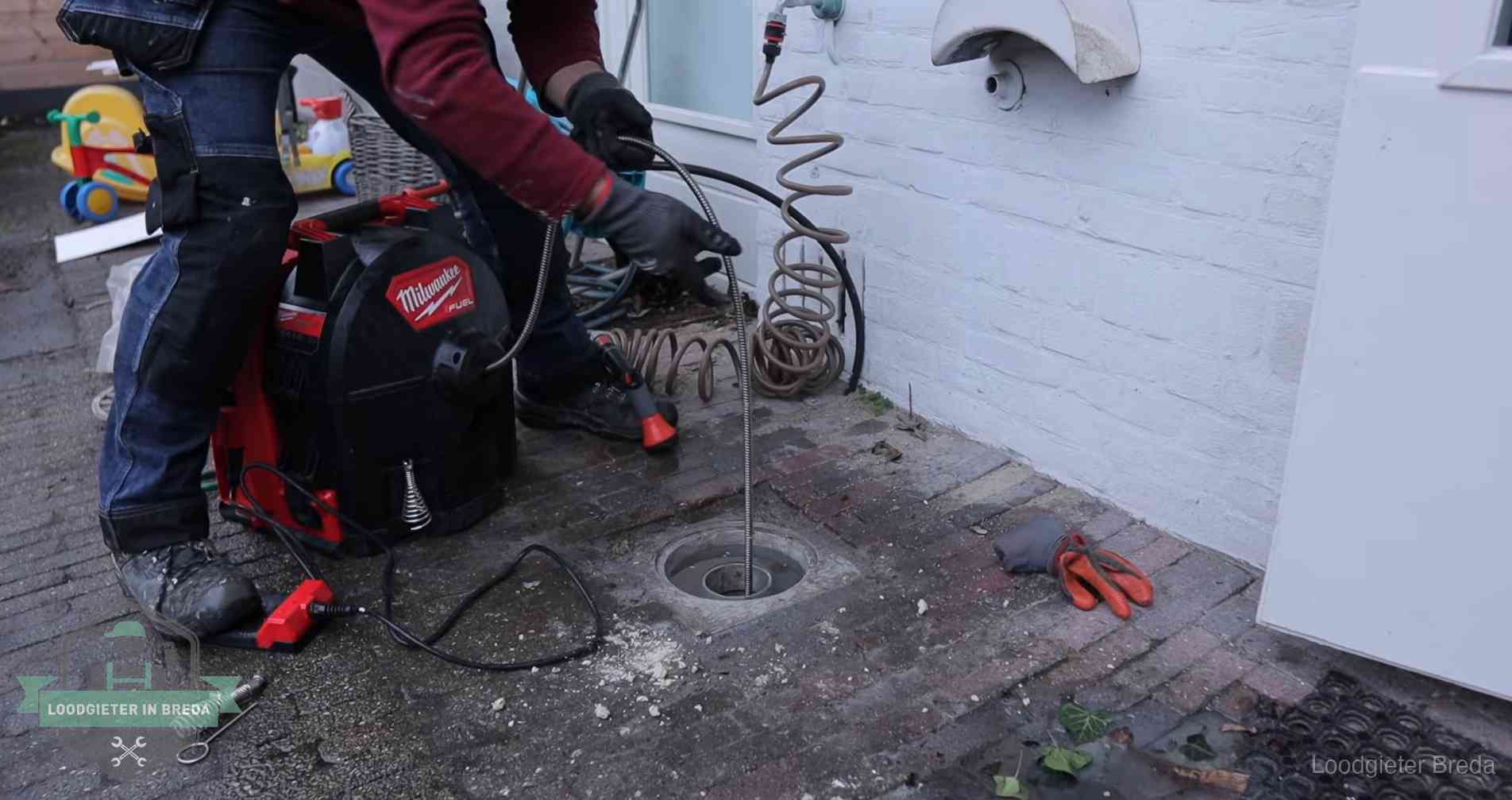 Ontstoppingsputje in de bestrating naast de gevel van een woning in Breda