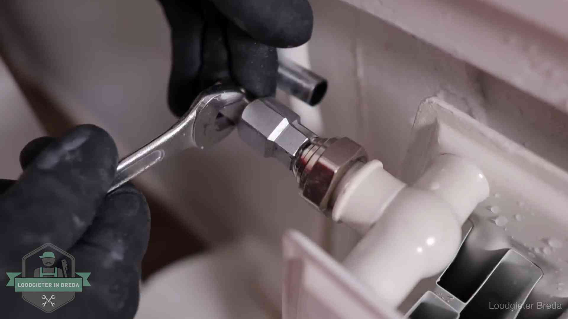 Steeksleutel draait een wartelkoppeling op een radiatorkraan aan in Breda