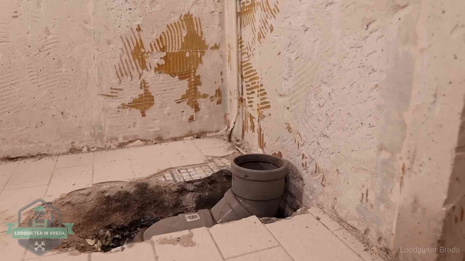 Opengebroken vloer met een nieuwe pvc-rioolbocht in een gegraven sleuf in Breda