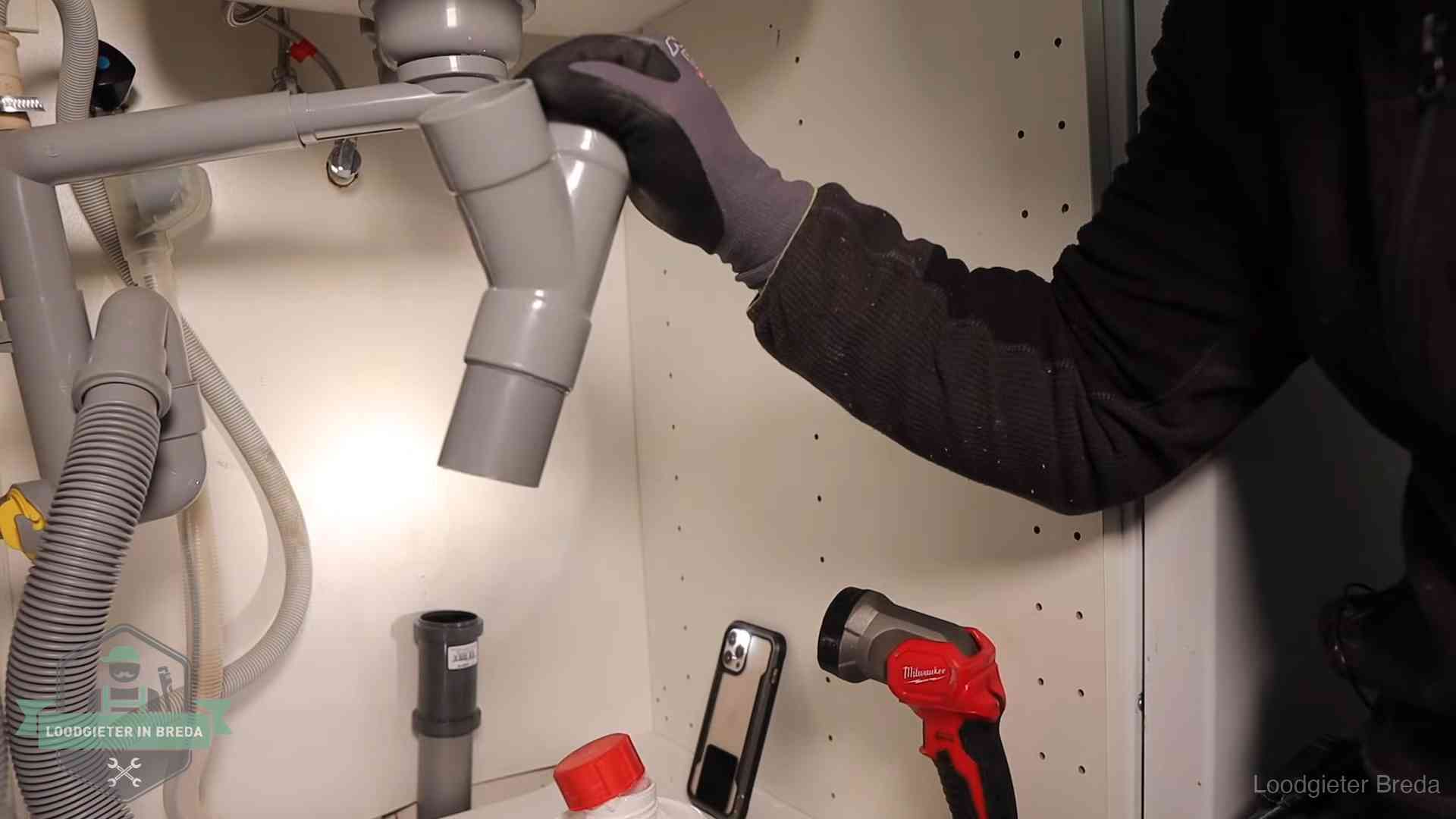 Loodgieter demonteert het sifon- en afvoerwerk onder een gootsteen in Breda bij stankklachten