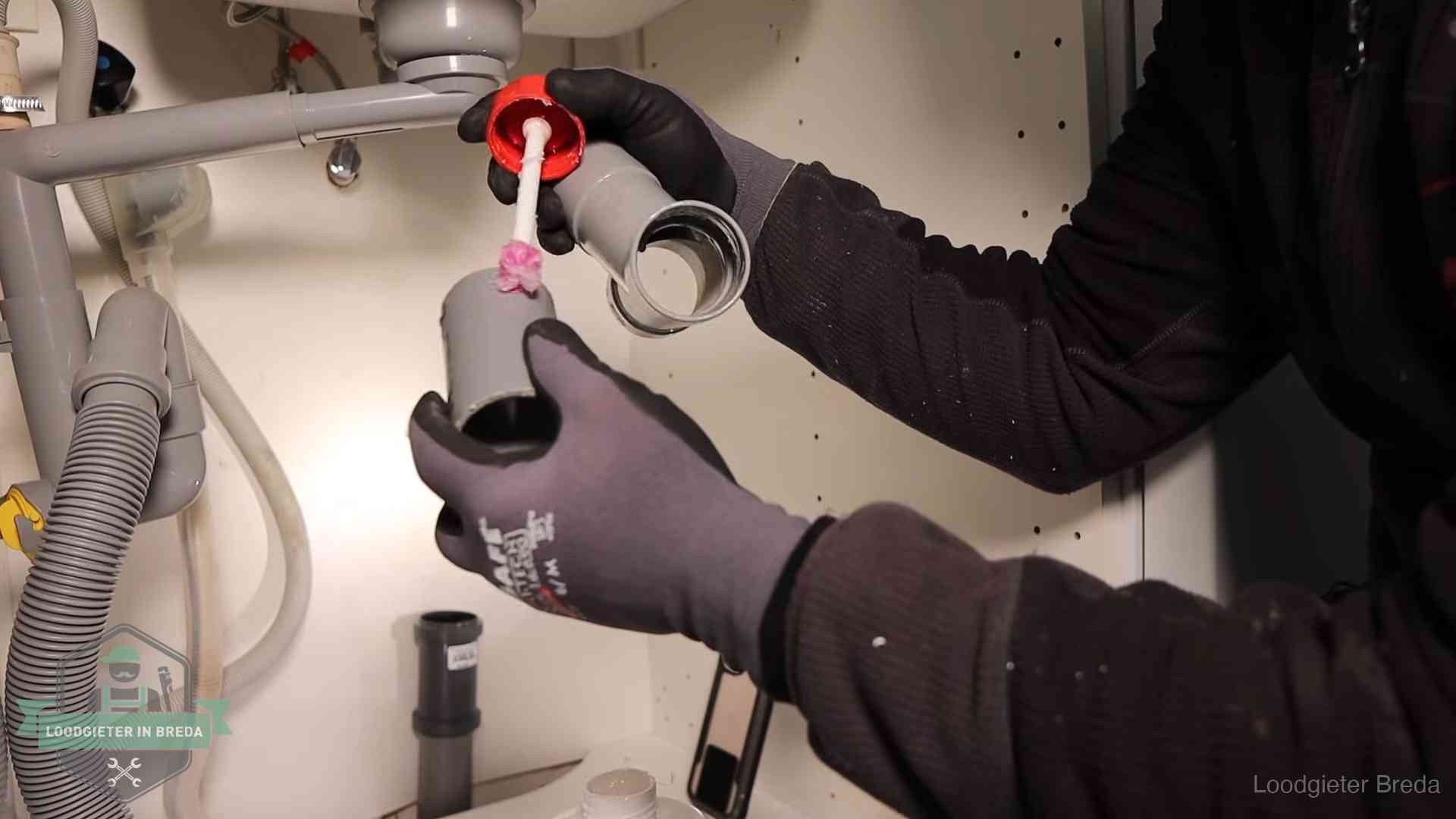 Loodgieter demonteert en reinigt de sifon onder een keukenkast in Breda